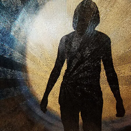 Una figura in controluce incisa su una lamina blu e oro