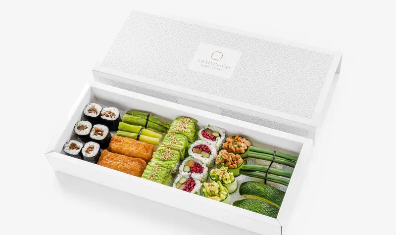 Una scatola bianca lunga aperta, piena di sushi in file ordinate