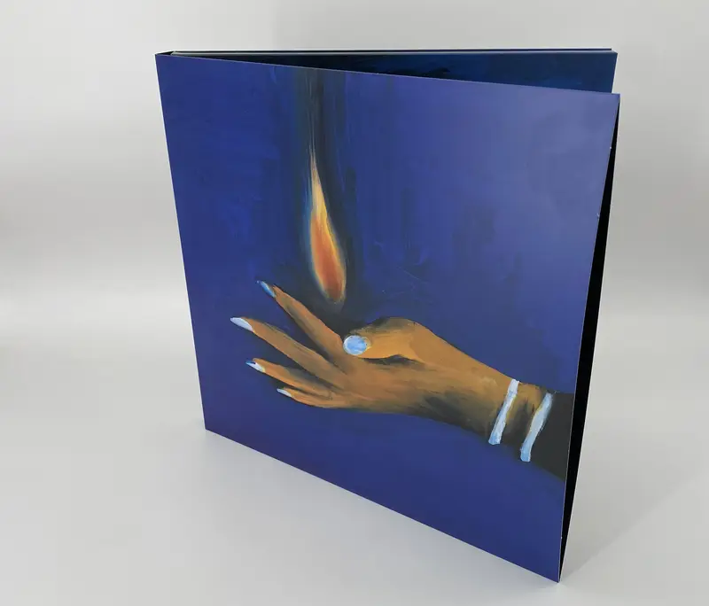 La copertina apribile blu del disco di Woodworm e Wudz, con la mano dipinta che regge una fiamma