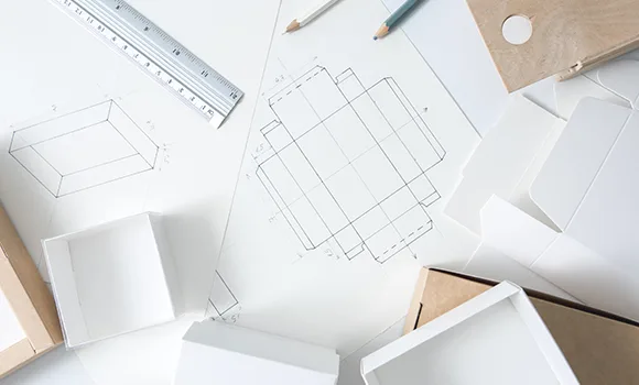 Fustelle disegnate a matita, un righello e i prototipi bianchi delle scatole