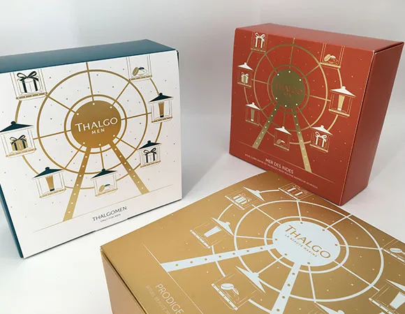 Un cofanetto Thalgo bianco e arancio con la ruota panoramica disegnata in oro, aperto accanto alla sua scatola